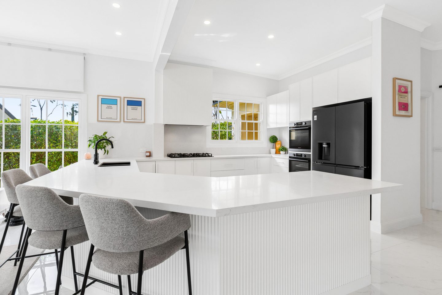 White kitchen with stone benchtops and a fluted breakfast bar
