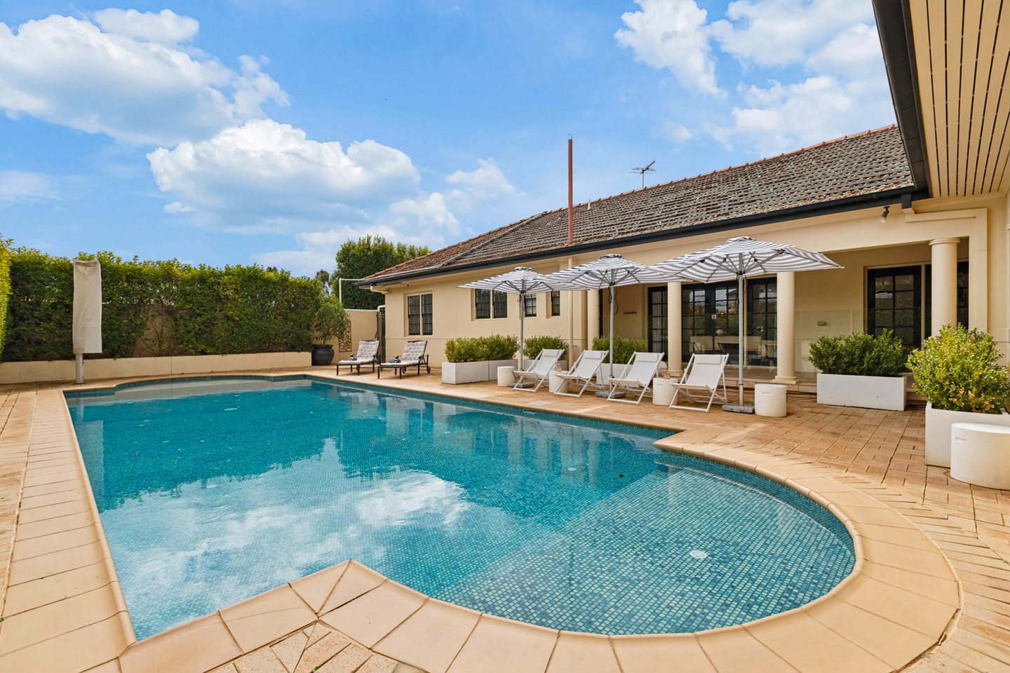 Villa Sol's curved swimming pool, cream façade and covered terrace